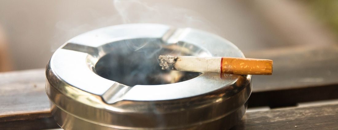 A cigarette balanced on an ashtray, smoke coming from it.