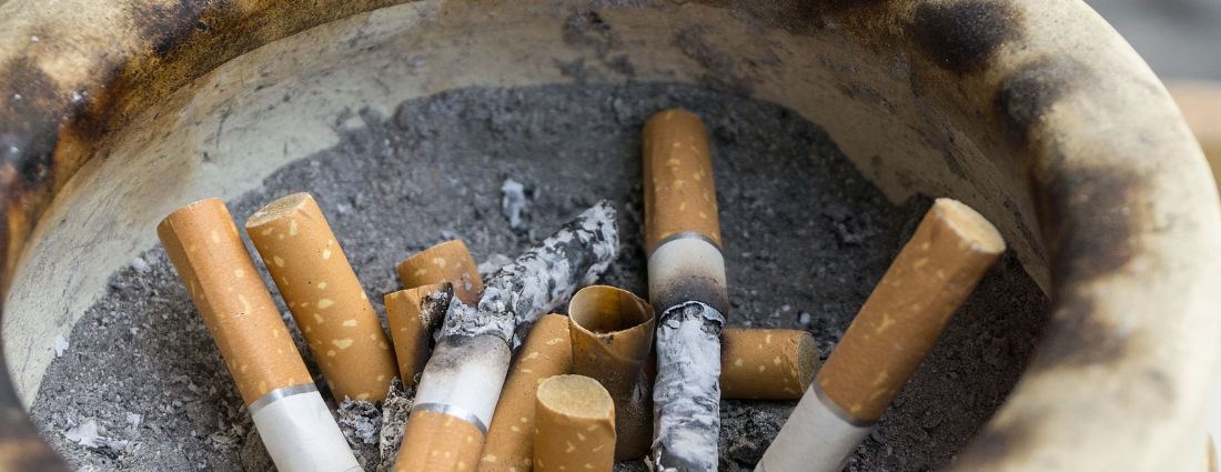 A stained ashtray with cigarettes